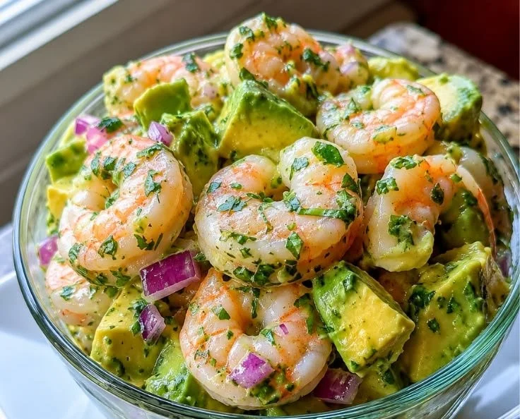Bright and creamy shrimp avocado salad in a summer bowl garnished with herbs