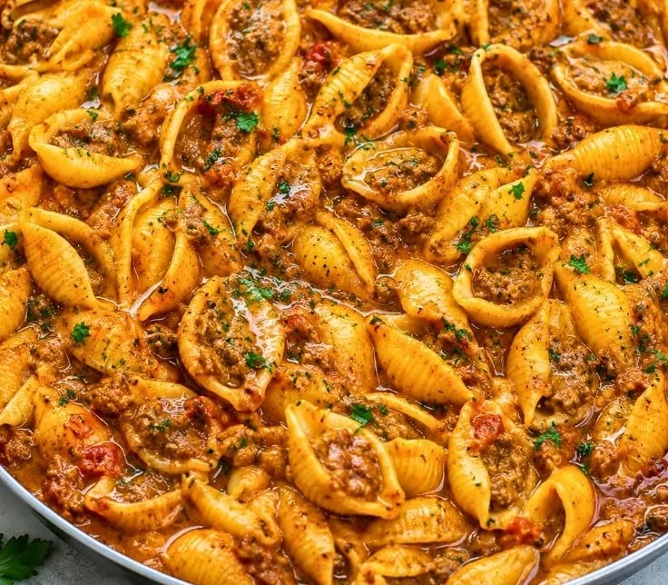 Creamy beef and shells dish served in a bowl with herbs and cheese