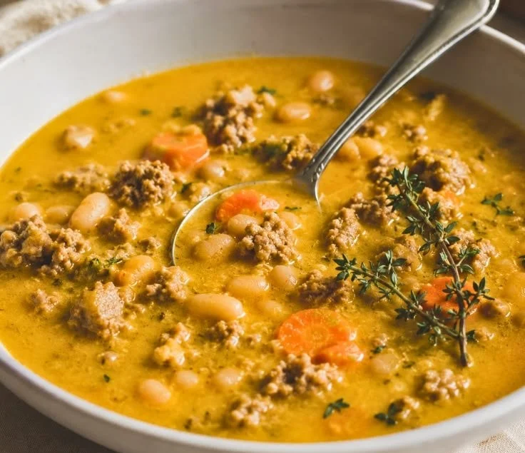 Bowl of creamy turkey pumpkin chili garnished with herbs.