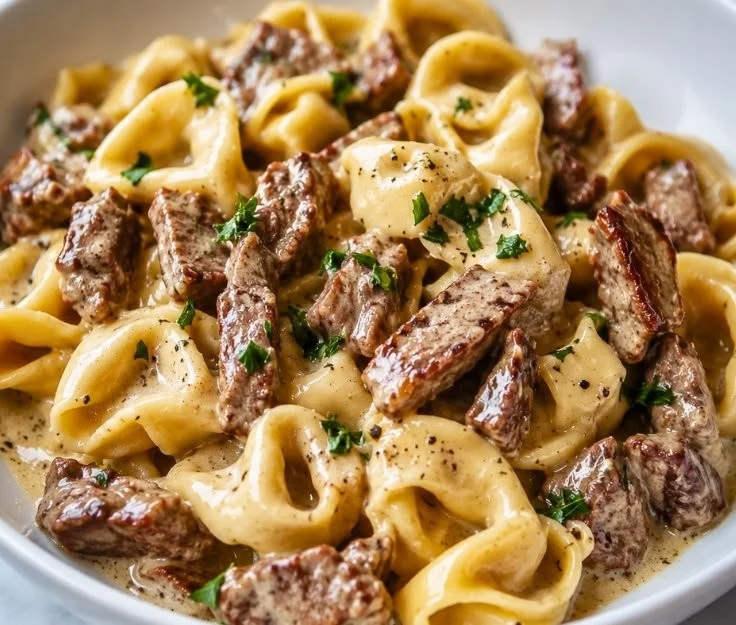 Philly Cheesesteak Tortellini Pasta topped with melty cheese and peppers