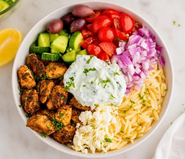 15-minute healthy chicken gyro bowls topped with fresh vegetables and sauce
