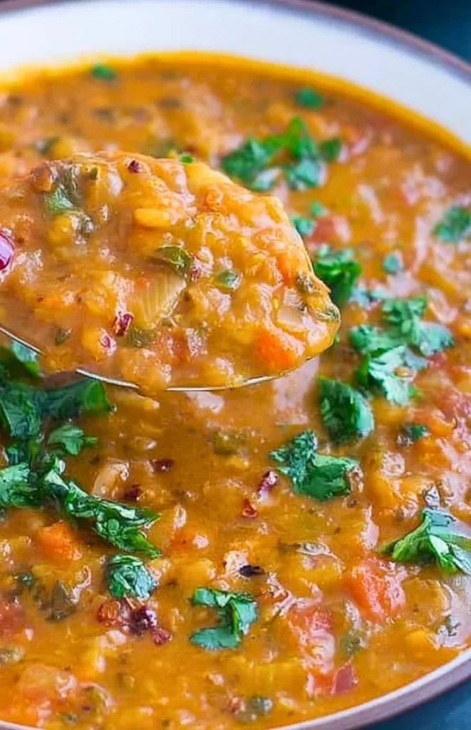 Bowl of Spicy Tomato Lentil Soup garnished with herbs and spices